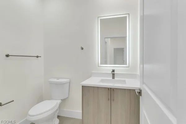 a bathroom with a toilet sink vanity and mirror