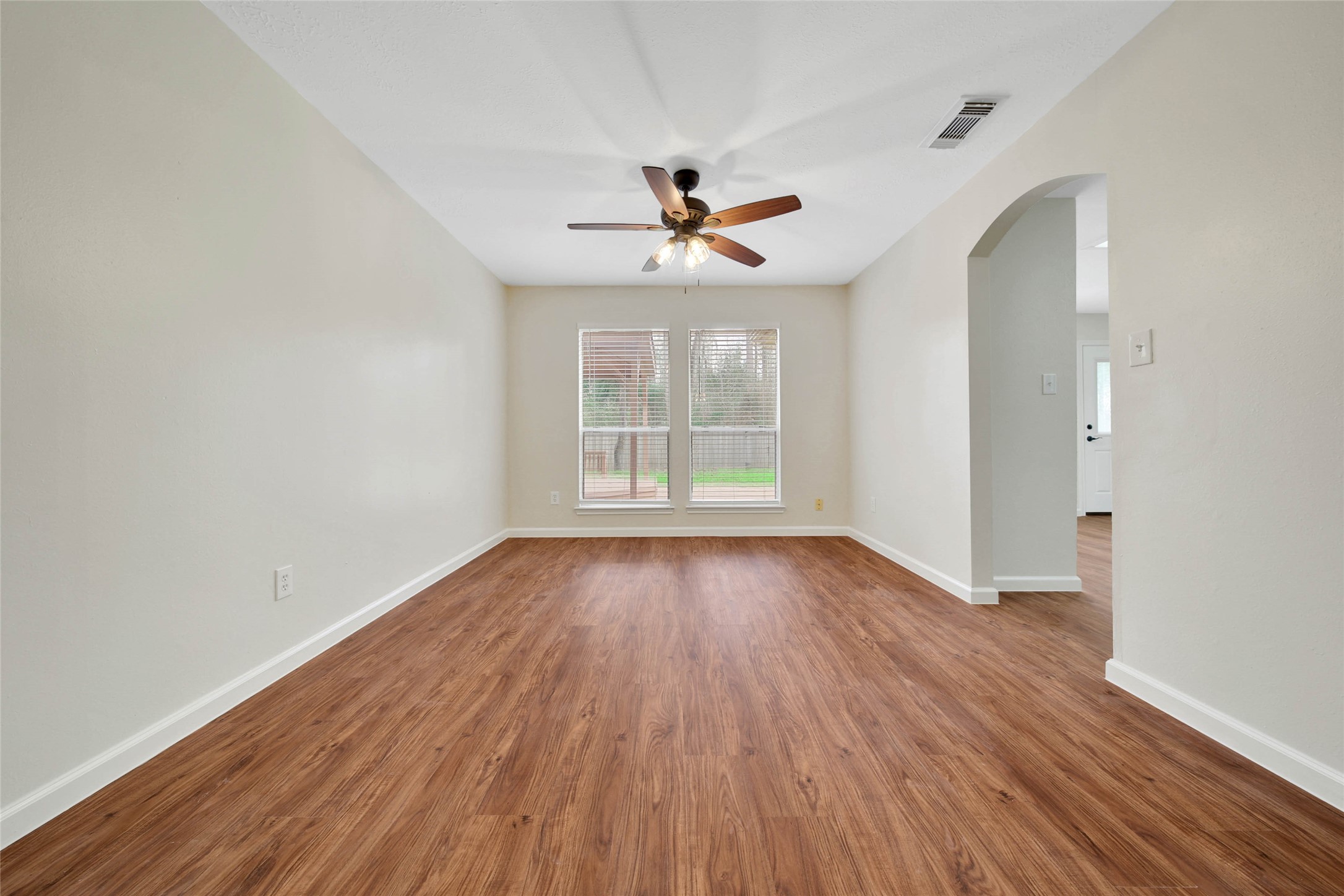 1427 Redwood Village Circle Spring, TX 77386 - Photo 13 of 43 an empty room with wooden floor chandelier fan and windows