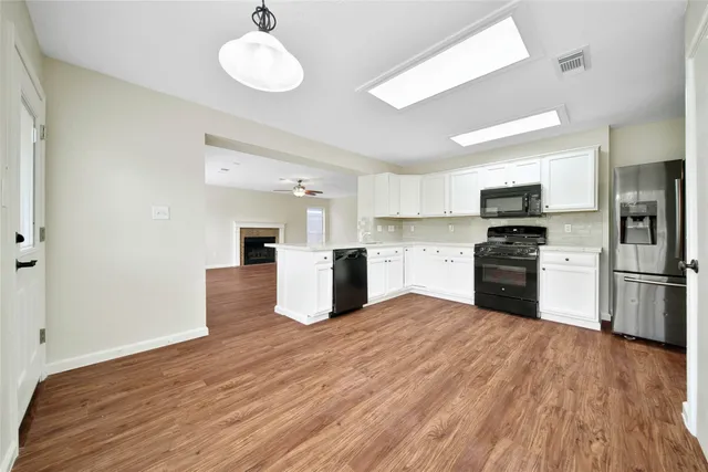 a kitchen with cabinets wooden floor and stainless steel appliances