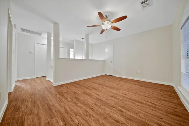 a view of empty room with wooden floor and fan