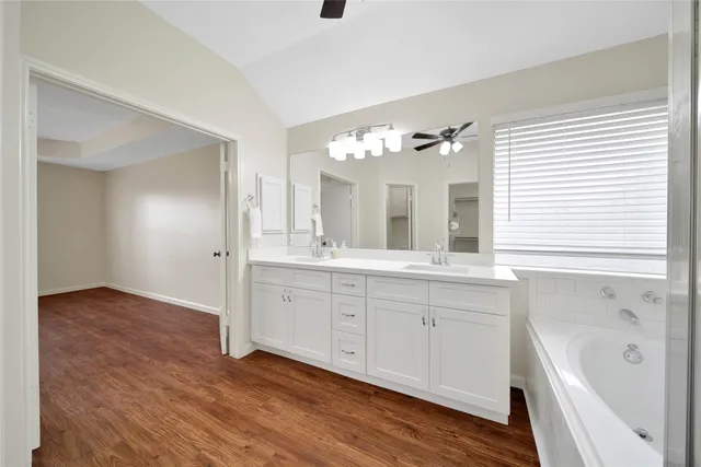 a bathroom with a double vanity sink a mirror and a bathtub