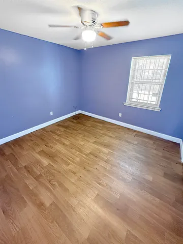 an empty room with windows and fan
