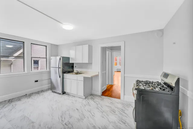 a kitchen with stainless steel appliances kitchen island granite countertop a refrigerator stove top oven and sink