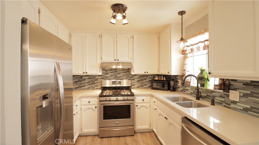 7331 Exeter Street, Unit 208 Paramount, CA 90723 - Photo 1 of 1 a kitchen with stainless steel appliances a sink a stove a refrigerator cabinets and a window