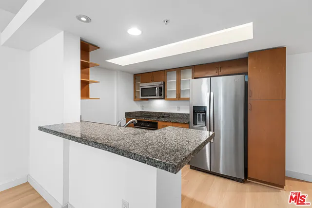 a kitchen with stainless steel appliances granite countertop a refrigerator a sink and a stove