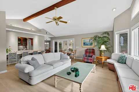 a living room with furniture kitchen view and a large window