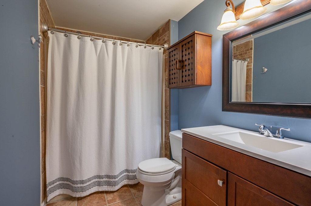 12 Perley Road, Unit 5 Derry, NH 03038 - Photo 12 of 21 a bathroom with a sink a toilet and shower curtain