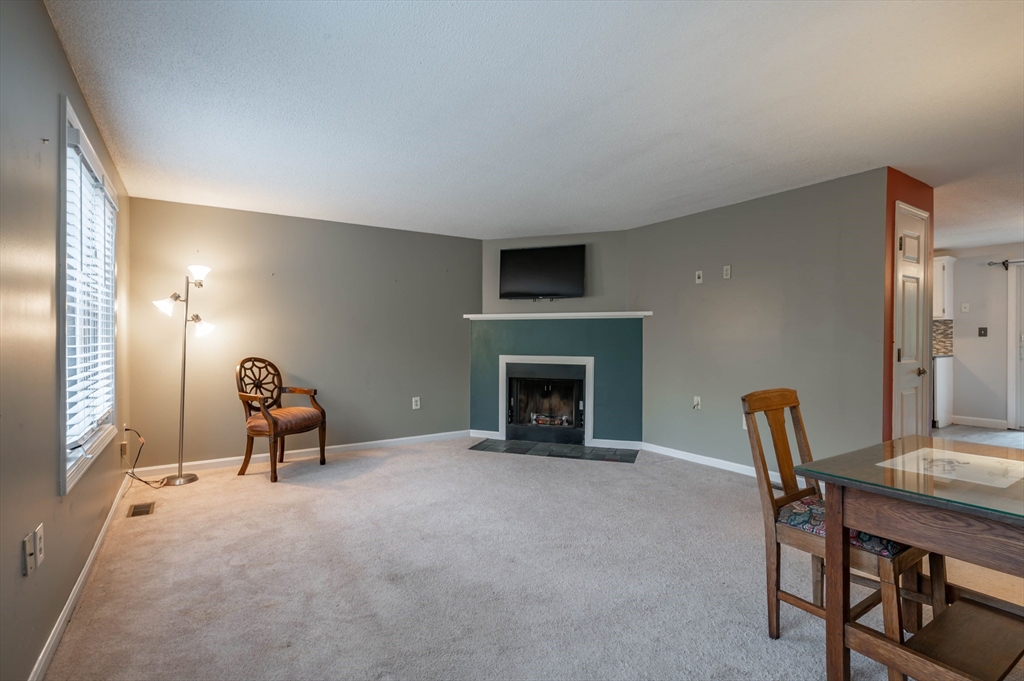 12 Perley Road, Unit 5 Derry, NH 03038 - Photo 6 of 21 a living room with furniture a fireplace and a table