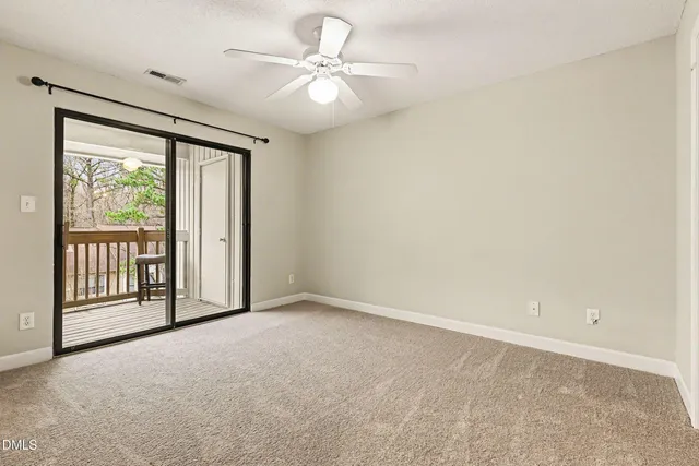 en empty room with windows and ceiling fan