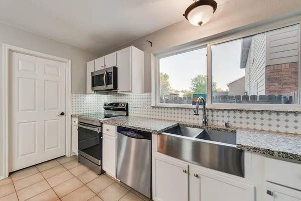 a kitchen with granite countertop a sink and a refrigerator