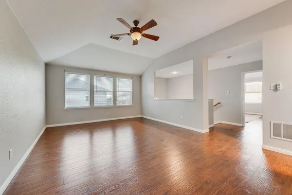 a view of an empty room with a window and wooden floor