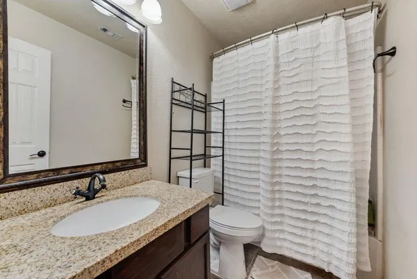 a bathroom with a granite countertop sink toilet and mirror