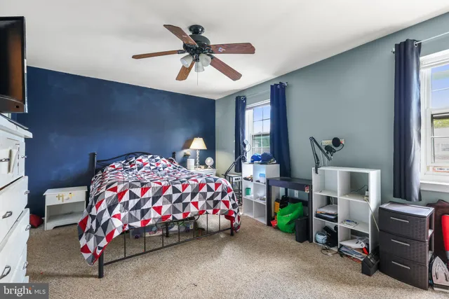 a bedroom with a bed a chandelier and a flat tv screen on dresser