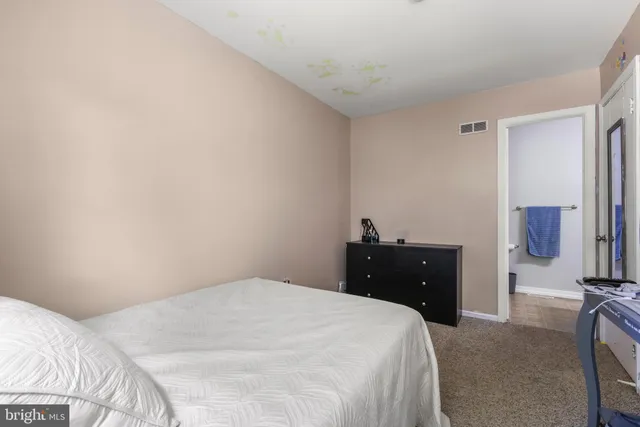 a bedroom with a bed and a potted plant on the dresser