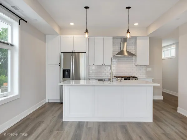 a kitchen with stainless steel appliances granite countertop a sink a stove a refrigerator cabinets and wooden floor