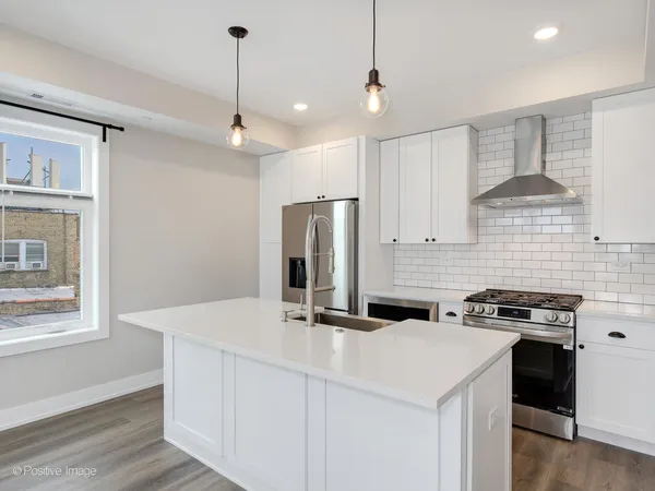 a kitchen with stainless steel appliances a sink a stove a refrigerator cabinets and wooden floor