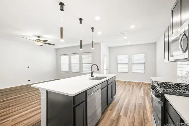 a open kitchen with kitchen island a sink stove and wooden floor