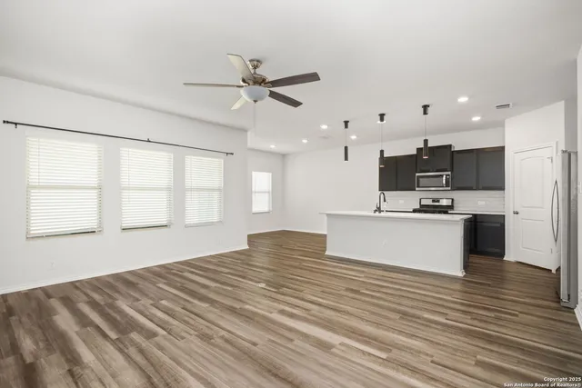 a view of kitchen with kitchen island wooden floor center island and stainless steel appliances
