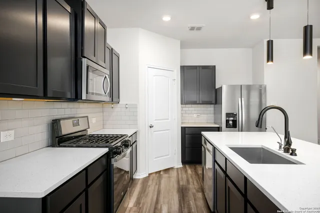 a kitchen with stainless steel appliances granite countertop a sink a stove and refrigerator