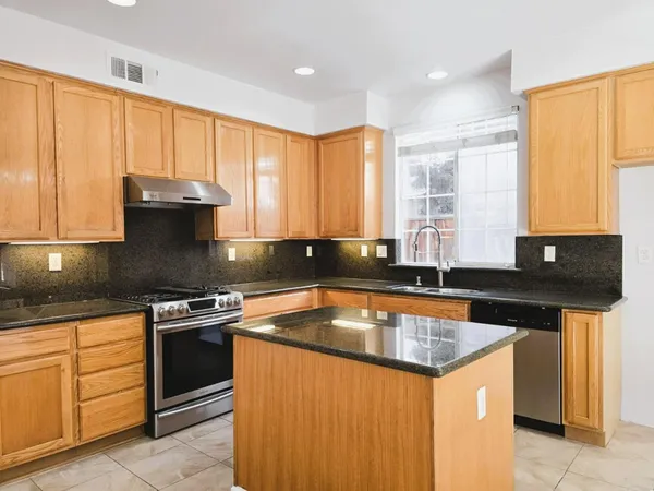 a kitchen with stainless steel appliances granite countertop a sink stove and cabinets