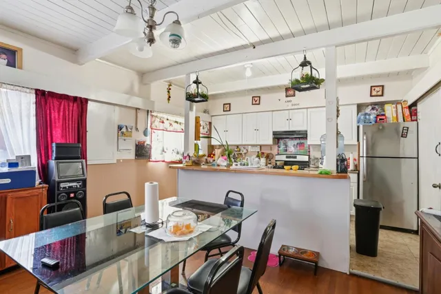 a open kitchen with stainless steel appliances granite countertop a refrigerator a sink dishwasher a dining table and chairs with wooden floor