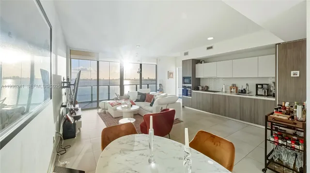 a living room with furniture kitchen view and a large window