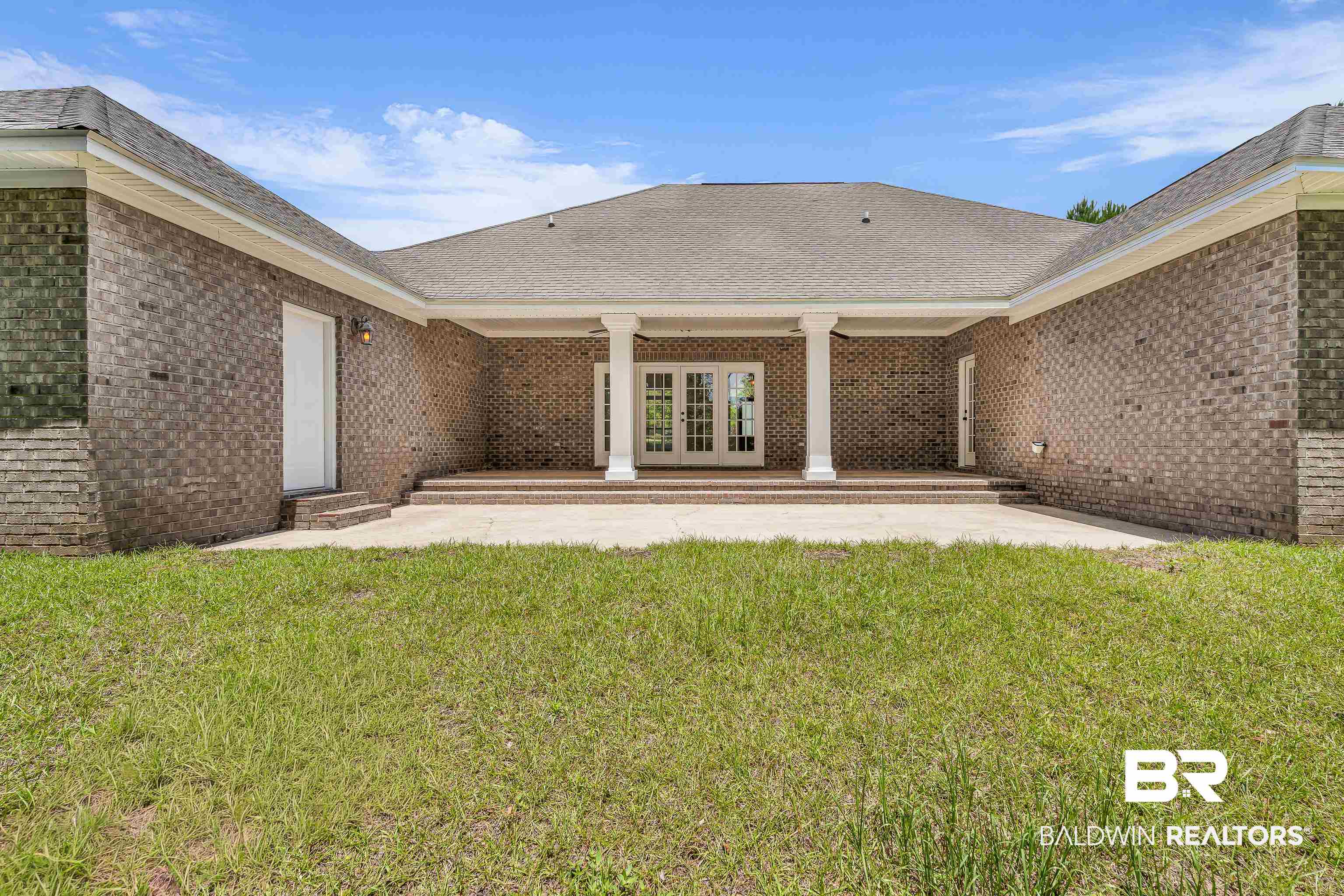 7495 Bromley Road Bay Minette, AL 36507 - Photo 4 of 31 Rear brick exterior featuring a covered patio with white columns and double French doors