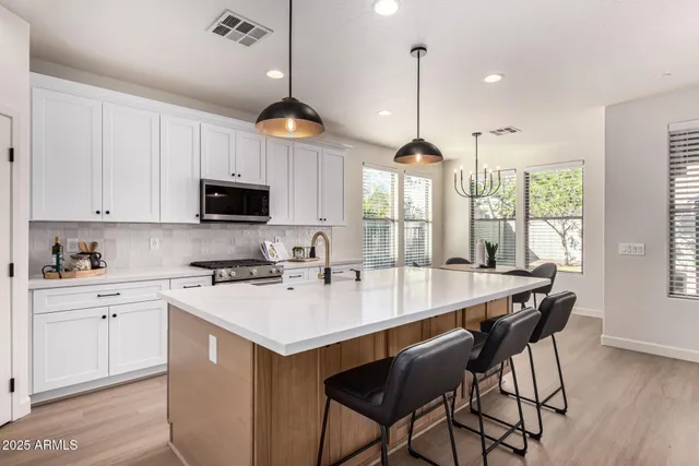 a large white kitchen with a stove a sink dishwasher and a fireplace with wooden floor