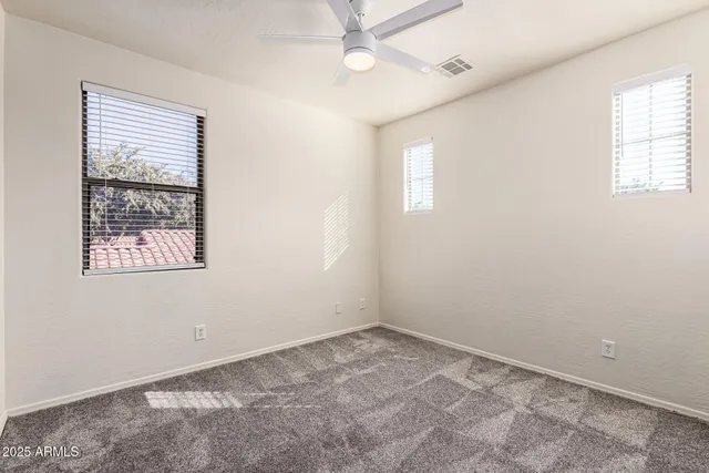an empty room with a ceiling fan and carpet