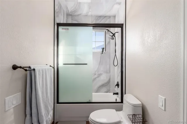 a bathroom with a granite countertop shower and a toilet