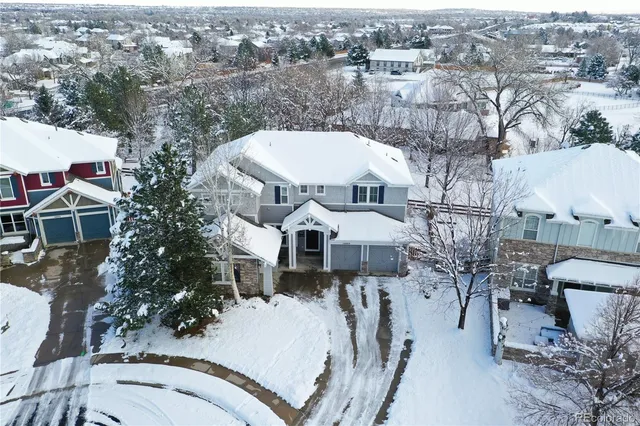 an aerial view of a house with a yard swimming pool and large trees