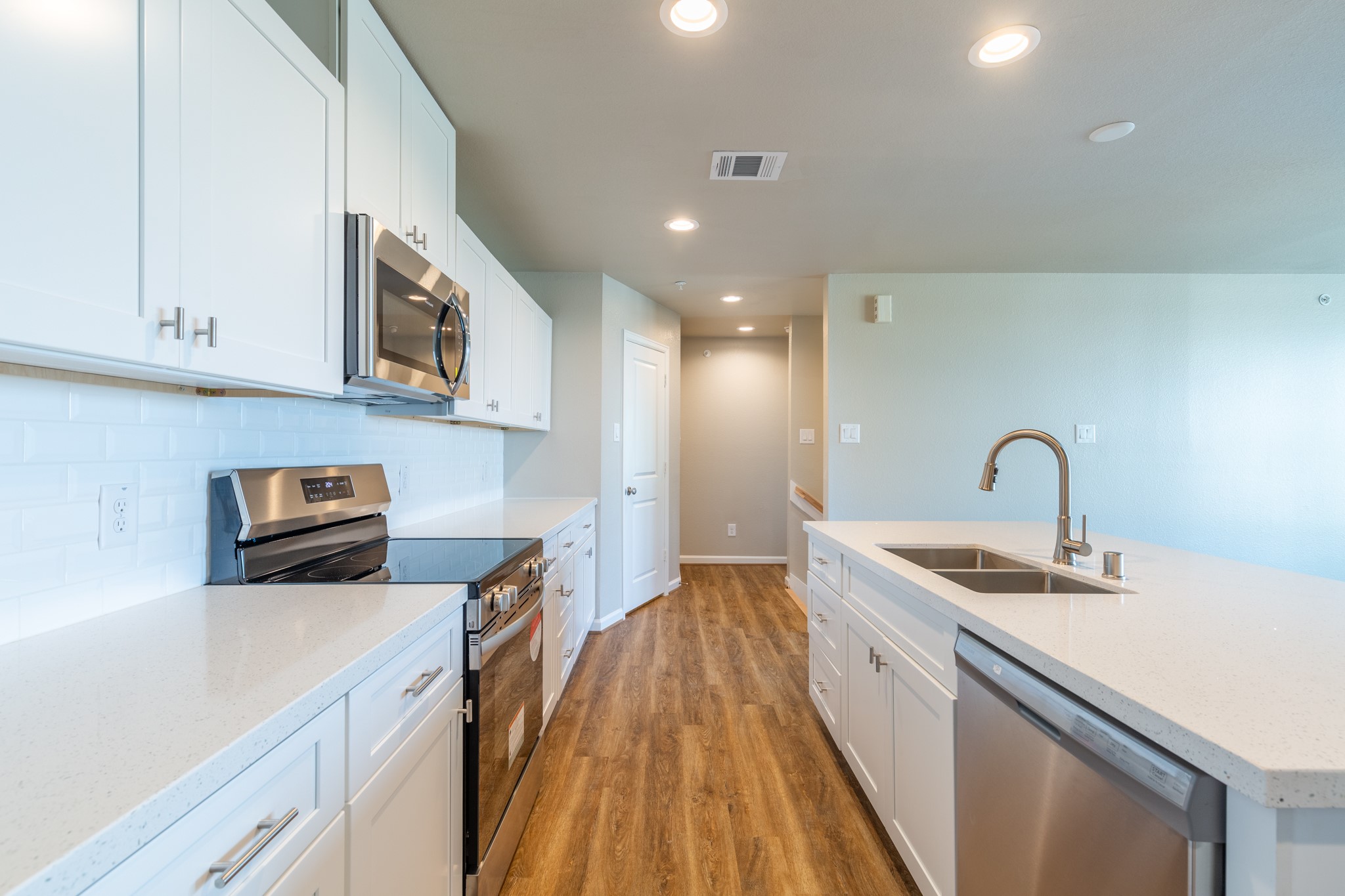 203 Park Place Circle, Unit D Waller, TX 77484 - Photo 11 of 29 a kitchen with stainless steel appliances granite countertop a sink a stove top oven a refrigerator with white cabinets and wooden floor
