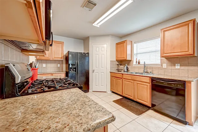 a kitchen with stainless steel appliances granite countertop a stove a sink and a refrigerator