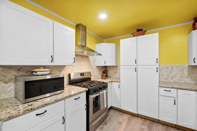 a kitchen with stainless steel appliances white cabinets and a stove top oven