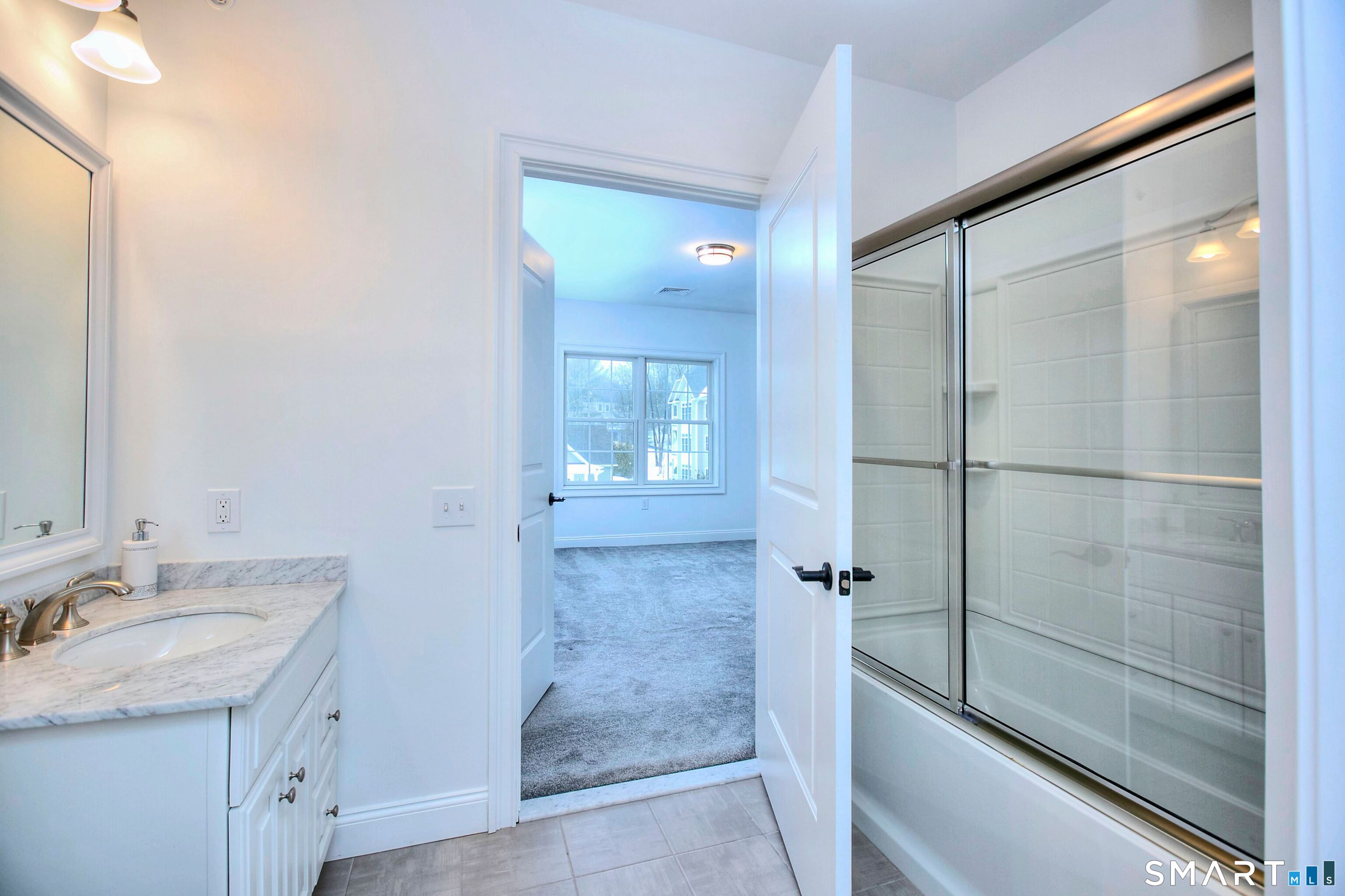 77 Sunset Lane, Unit 335 Ridgefield, CT 06877 - Photo 14 of 25 a bathroom with a granite countertop sink a mirror and shower