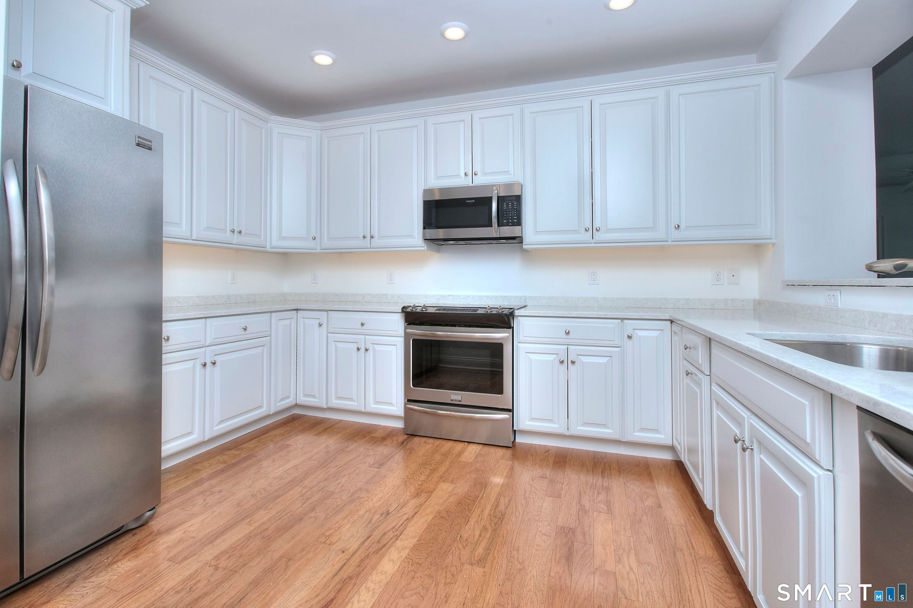 77 Sunset Lane, Unit 335 Ridgefield, CT 06877 - Photo 3 of 25 a kitchen with white cabinets and stainless steel appliances