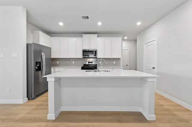 a view of kitchen with stainless steel appliances granite countertop a stove a refrigerator a sink dishwasher and a refrigerator with wooden floor