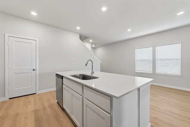 a kitchen with a sink a stove and wooden floor