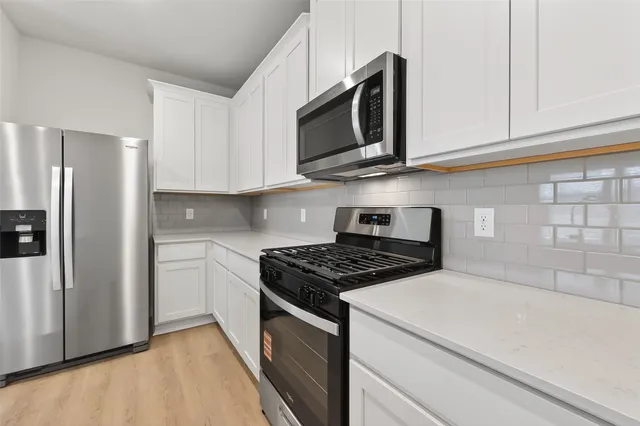 a kitchen with stainless steel appliances granite countertop white cabinets and a stove a refrigerator with white cabinets