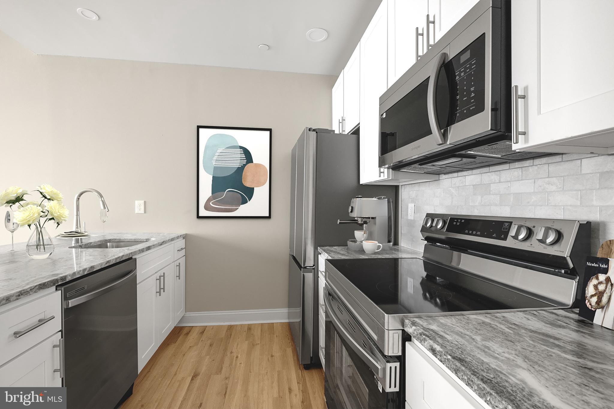 1420-22 Chestnut Street, Unit 503 Philadelphia, PA 19102 - Photo 16 of 35 a kitchen with stainless steel appliances a stove a sink and a microwave