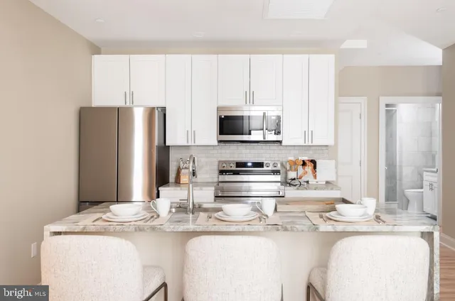 a kitchen with stainless steel appliances granite countertop a sink a stove a refrigerator with white cabinets