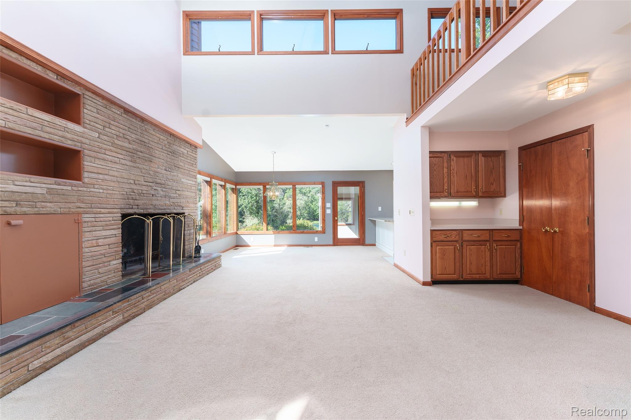 3166 Bigelow Road Howell, MI 48855 - Photo 5 of 50 Spacious great room featuring a floor-to-ceiling stone fireplace, high vaulted ceilings, and a wall of windows