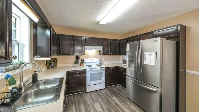 a kitchen with stainless steel appliances granite countertop a refrigerator sink and stove