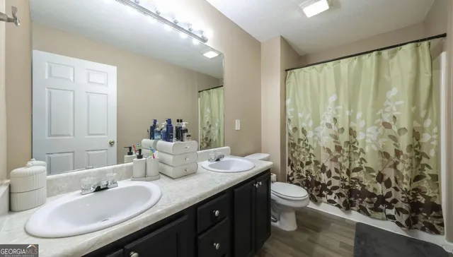 a bathroom with a granite countertop sink and a mirror with toilet