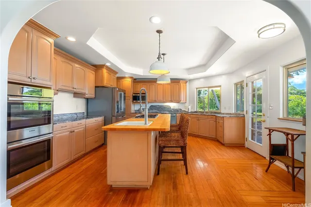 a kitchen with stainless steel appliances kitchen island granite countertop wooden floors and white cabinets