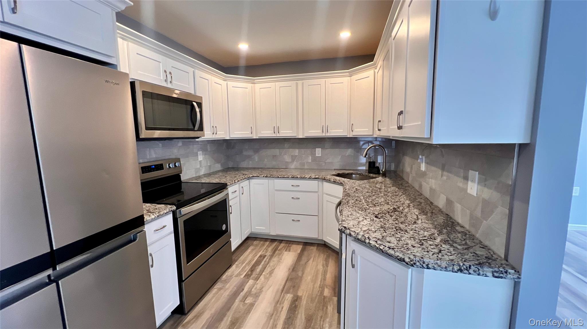421 Weymouth Court, Unit D Ridge, NY 11961 - Photo 7 of 21 a kitchen with stainless steel appliances granite countertop a stove a sink and a refrigerator