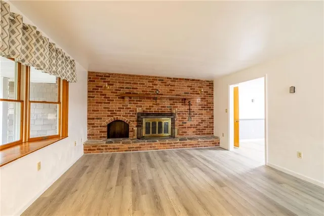 a view of a living room with a fireplace and wooden floor