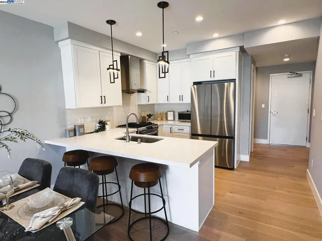 a kitchen with stainless steel appliances kitchen island granite countertop a table chairs and a refrigerator