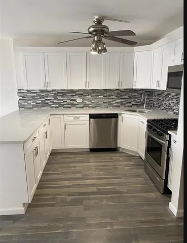 a kitchen with kitchen island granite countertop a sink cabinets and stainless steel appliances