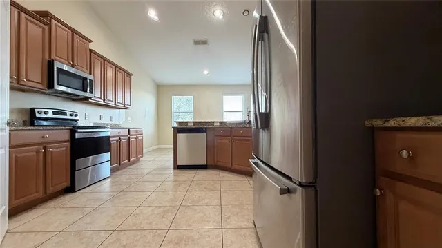 a kitchen with granite countertop wooden cabinets and a stove top oven